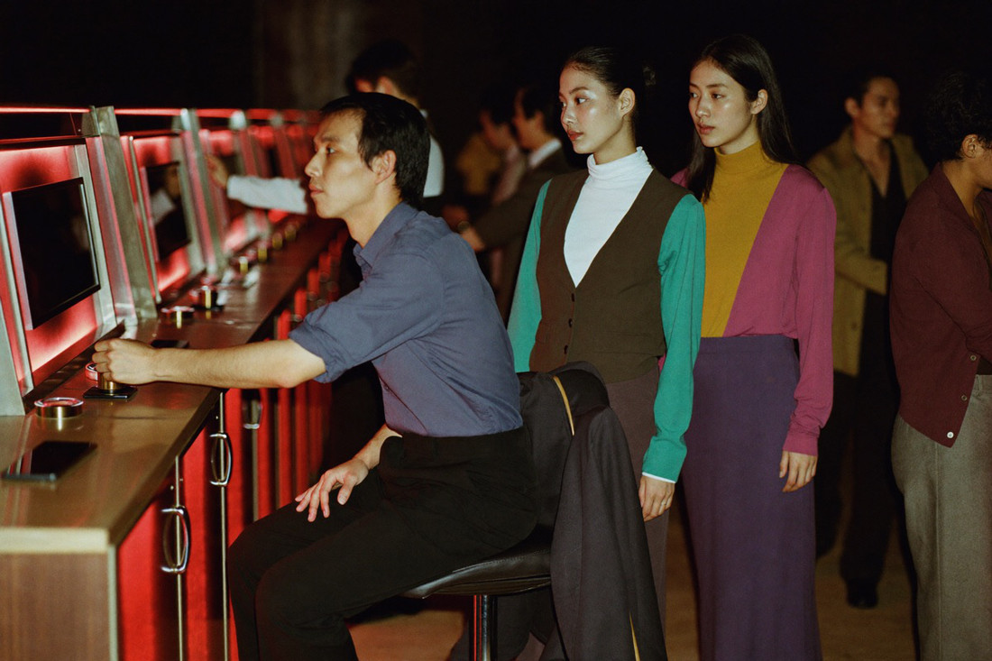A man in a buttoned shirt dropping back onto the stool at the slot cabinet he left, his jacket still over the backrest