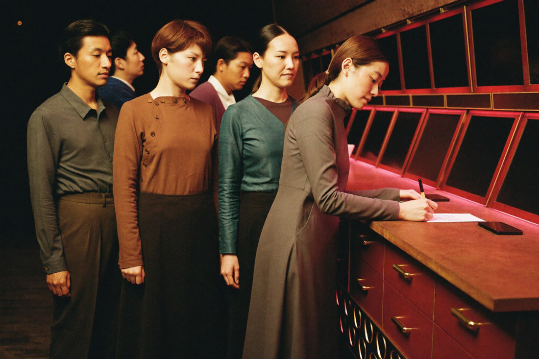 A new player filling a short paper form with a pen at the member desk while a clerk in a waistcoat points at the line