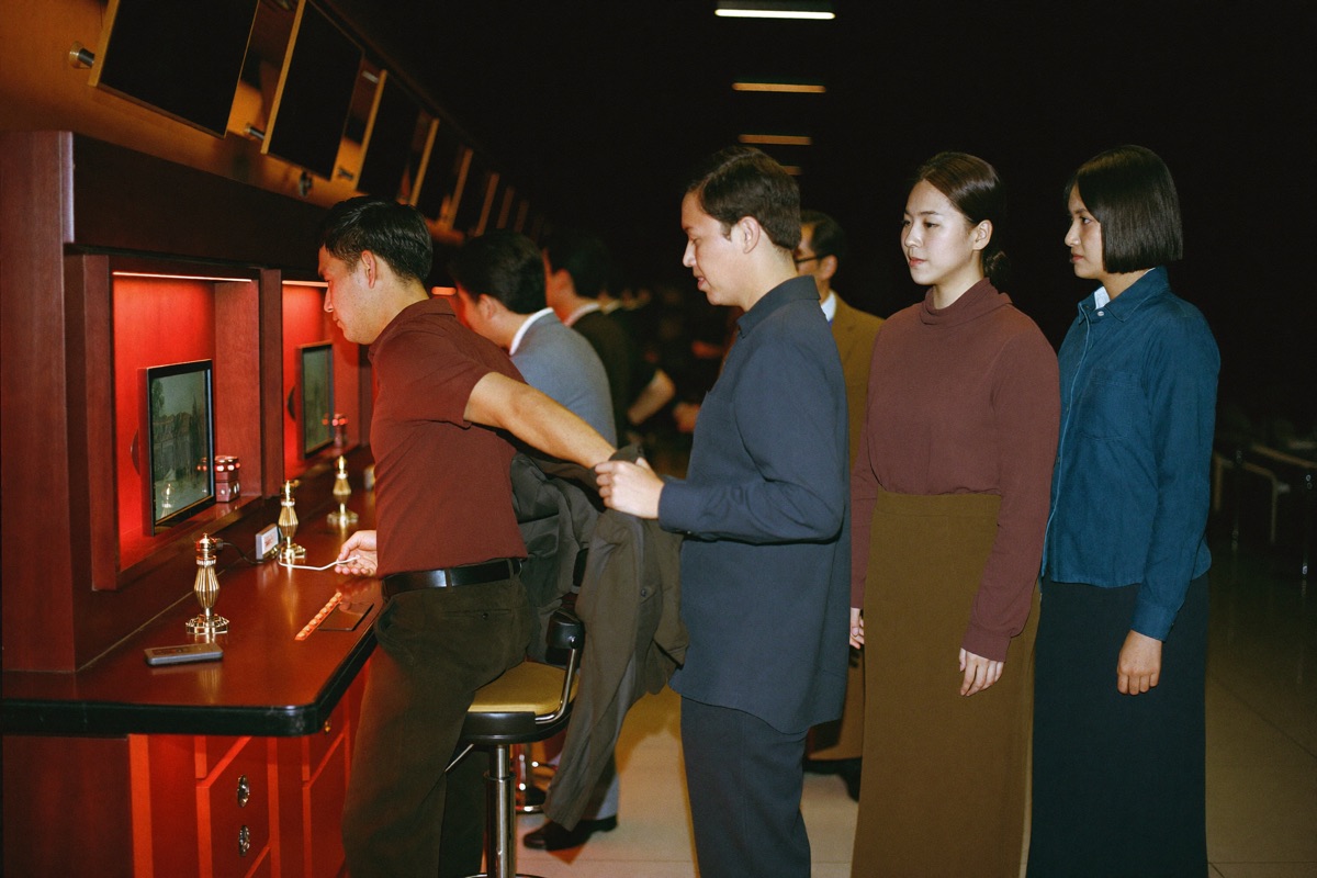A man in a polo shirt standing up from a slot stool and taking his jacket off the backrest, turning away from the lit cabinet